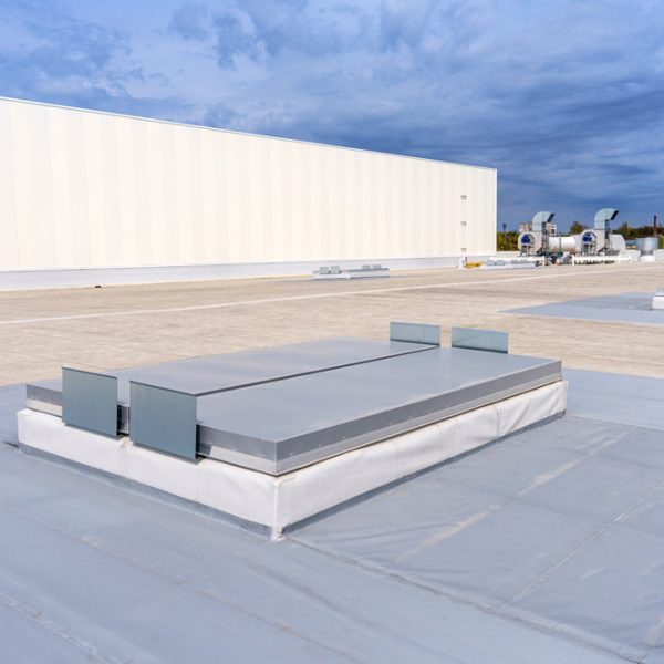 White metal sheet rooftop wall on commercial building with blue sky.